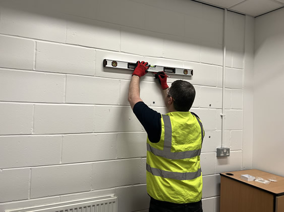 Rapid engineer holding a spirit level to a wall