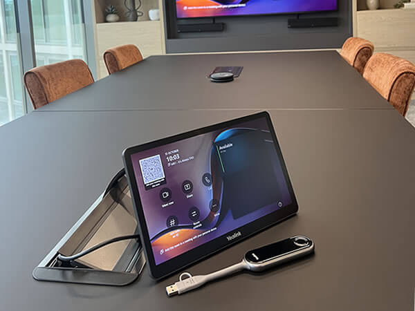 Yealink Teams Room touchscreen console and wireless sharing device on a conference table in Synextra’s boardroom AV installation.