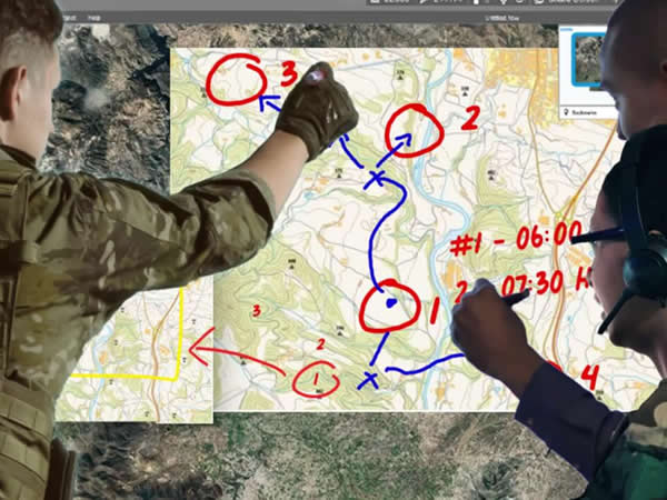 Military personnel using interactive digital map display for tactical planning and mission coordination.